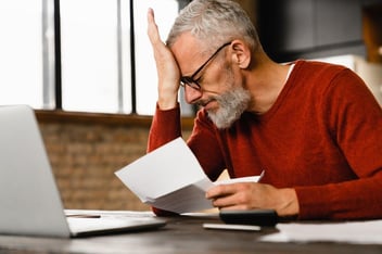 Homem com mão na cabeça estressado pela fatura do cliente